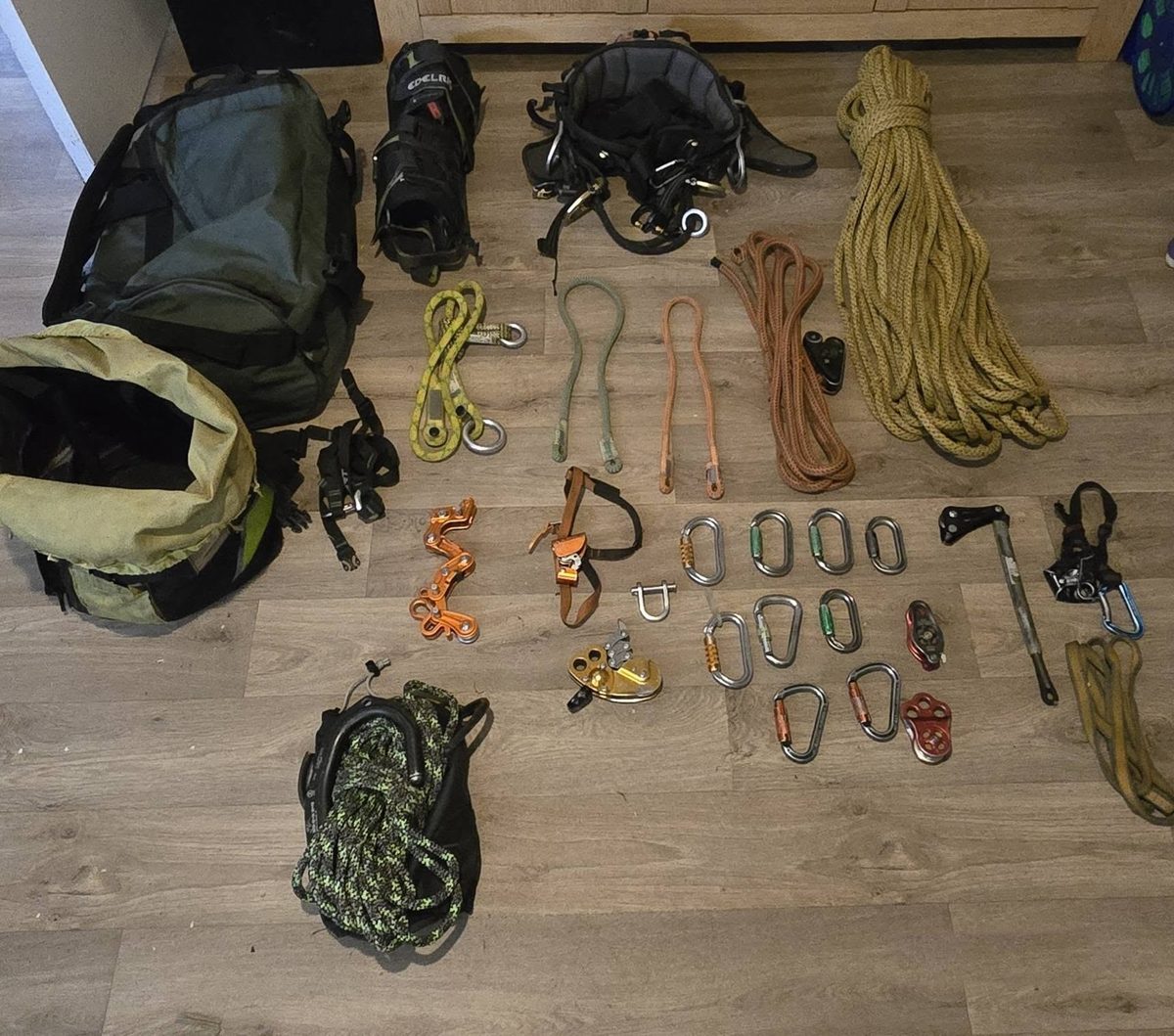 A full climbing kit laid out on the floor: harness, climbing and rigging ropes, lanyards, rope wrenches, pulleys, karabiners and kit bags